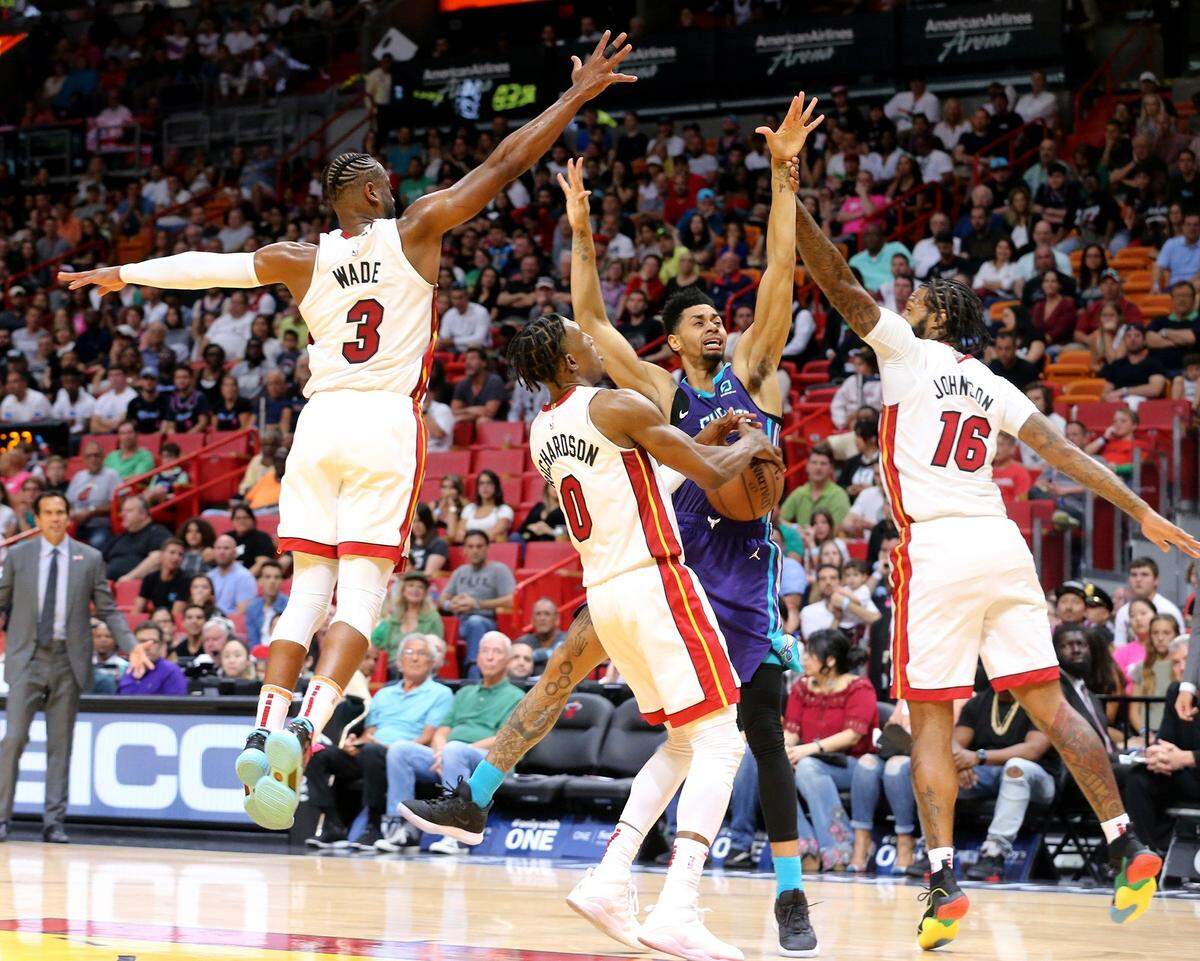 Miami Heat Dwyane Wade (3), Josh Richardson (0) and James Johnson (16) defend Charlotte Hornets Jeremey Lamb (3) in the fourth quarter at the AmericanAirlines Arena in Miami, Florida, Sunday, March, 17, 2019.