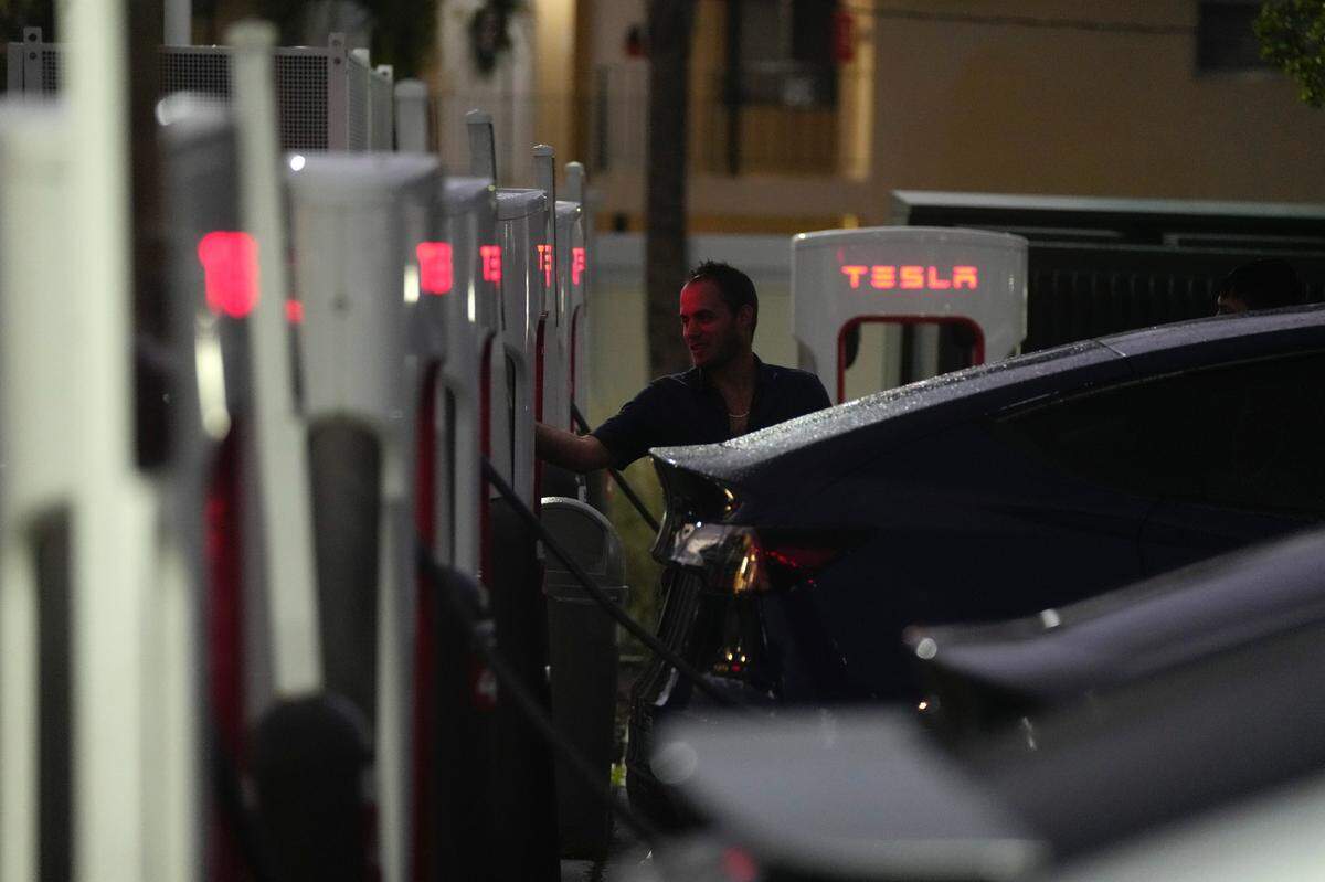 A driver charges his car at a Tesla Supercharger station, Wednesday, Nov. 16, 2022, in Miami. A tweet from Elon Musk indicating that Tesla might allow some owners who are testing a “Full Self-Driving” system to disable an alert that reminds them to keep their hands on the steering wheel has drawn attention from U.S. safety regulators. (AP Photo/Rebecca Blackwell, File)