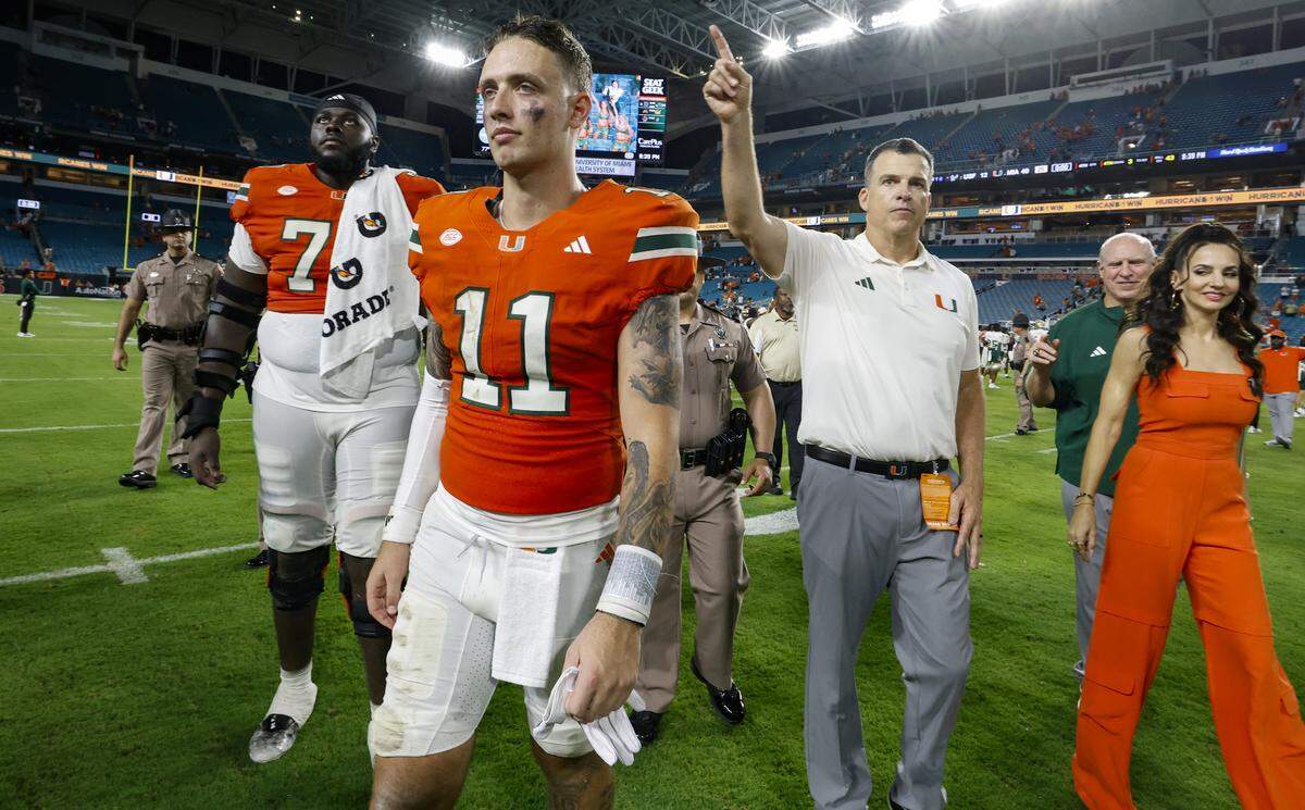 Miami Hurricanes quarterback Carson Beck (11) and head coach Mario Cristobal walk off the field after the Canes defeat the South Florida Bulls during their NCAA football game at Hard Rock Stadium in Miami Gardens, Florida, on Saturday, September 13, 2025.