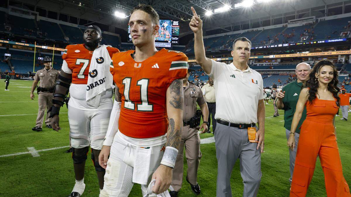 Miami Hurricanes quarterback Carson Beck (11) and head coach Mario Cristobal walk off the field after the Canes defeat the South Florida Bulls during their NCAA football game at Hard Rock Stadium in Miami Gardens, Florida, on Saturday, September 13, 2025.