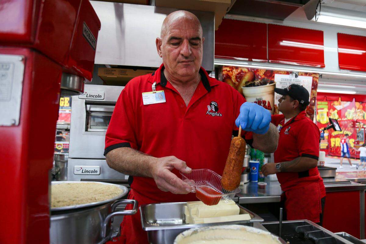 Ziggy Viscusi prepares a quarter pound of mozzarella cheese stick during the opening day of the Miami-Dade County Youth Fair at the Miami-Dade Fair & Expo Center in Miami, Florida, on Thursday, March 17, 2022.