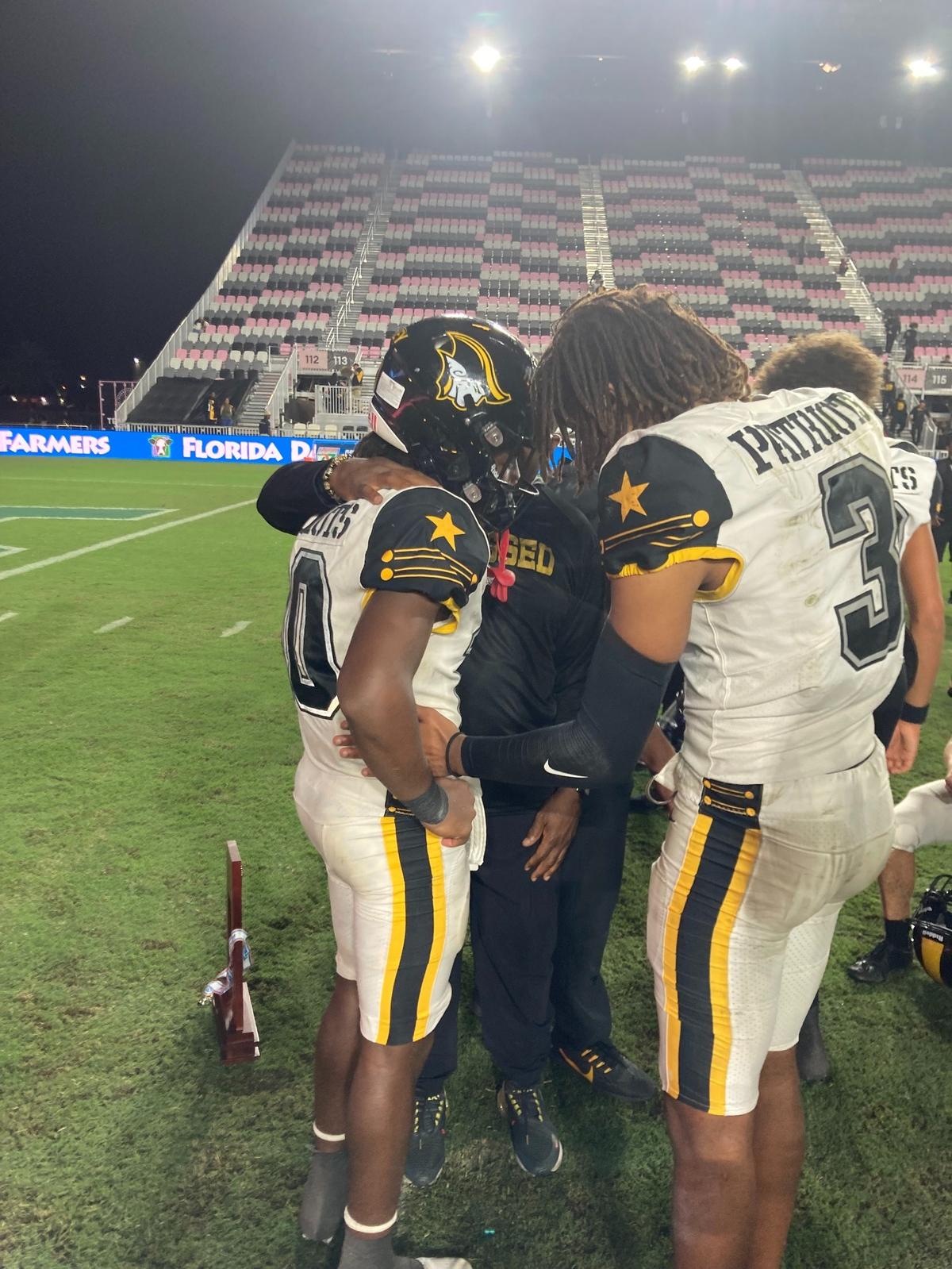 Teammates and coaches console Malachi Toney (left) after a late fumble ended Plantation American Heritage’s comeback effort in the Class 2M championship