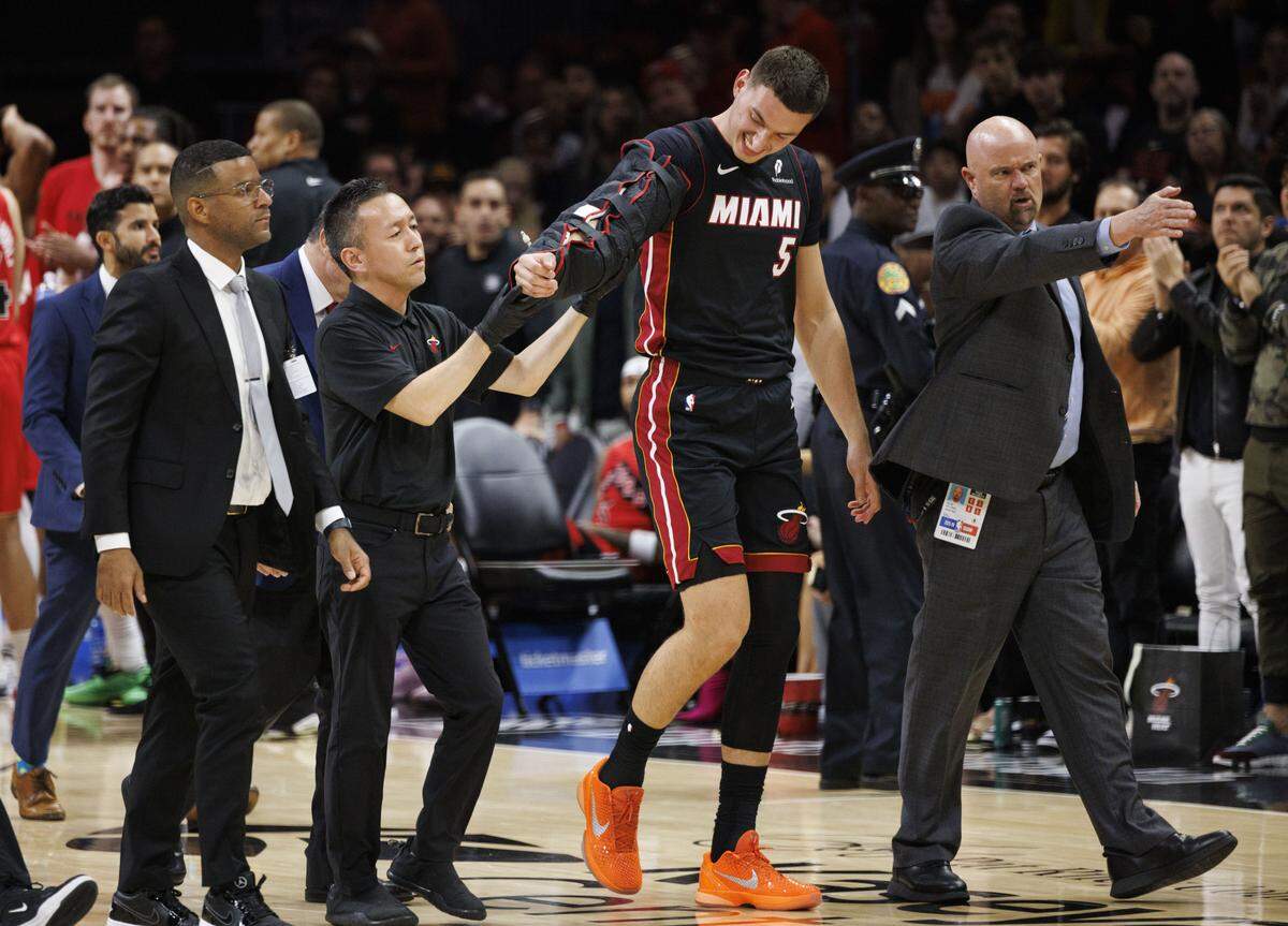 Miami Heat forward Nikola Jovic (5) is escorted off the court after getting fouled by Toronto Raptors forward Collin Murray-Boyles (12) and hurting his arm during the first half of a game on Monday, Dec. 15, 2025, at the Kaseys Center in downtown Miami, Fla.