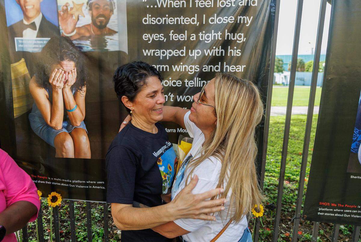 The tragedy of losing their sons to gun violence joined Pascale Marra (left) and Aymee Sanchez, they hug each other during the opening of The “SHOT: We the Mothers Miami” exhibition by photographer Kathy Shorr that consists of a powerful display of large-scale vinyl prints featuring portraits, objects, and the words of 44 mothers who have lost children to gun violence in the Miami area Wednesday September 27, 2023.