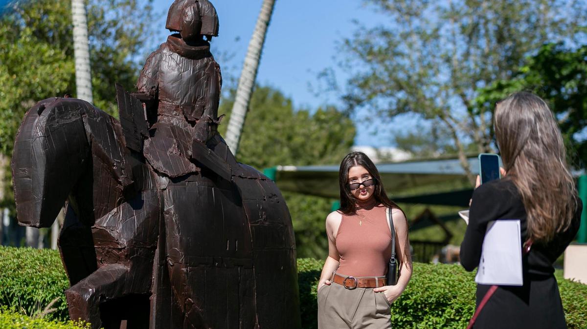 Mariana Bofill takes a photo of her daughter, Sabrina Carrillo, in front of a sculpture by renowned Spanish artist Manolo Valdes at the Downtown Doral Park in Doral, Florida on Saturday, December 5, 2020. Doral Mayor Juan Carlos Bermudez and members of the Doral Contemporary Art Museum (DORCAM) held an opening ceremony for the art exhibition on Saturday. At least 16 sculptures by Valdes will be installed across Doral in hopes of attracting an art scene to the city.
