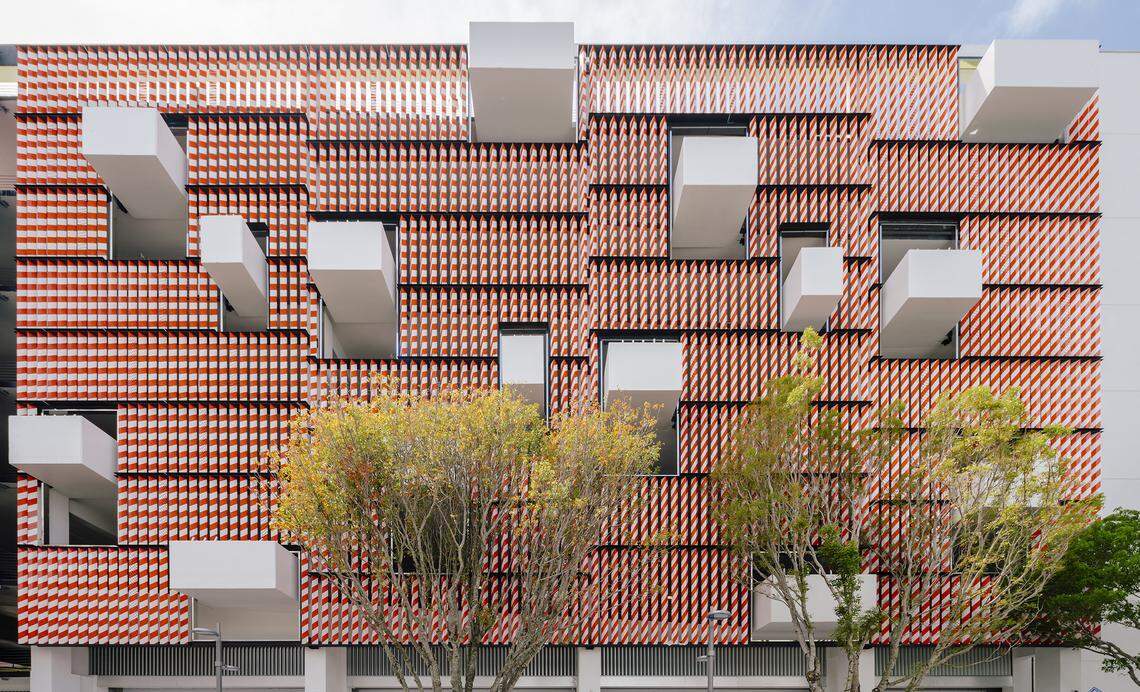 The Museum Garage's "Barricades" facade, by architect Terence Riley, consists of a screen of orange- and white-striped metal traffic barricades punctuated by protruding concrete planters.