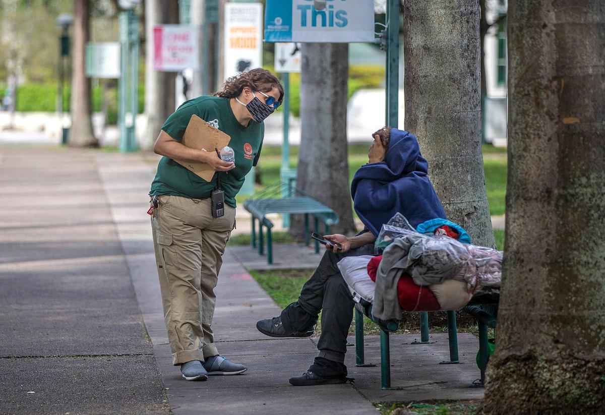 In this file photo from Jan. 28, 2022, Maxie Espinosa, a City of Miami outreach referral specialist, offers to bring someone in from the cold in downtown Miami.