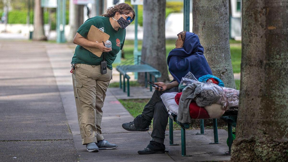 Maxie Espinosa, a City of Miami outreach referral specialist, offers to bring someone in from the cold on Jan. 28, 2022, in downtown Miami.