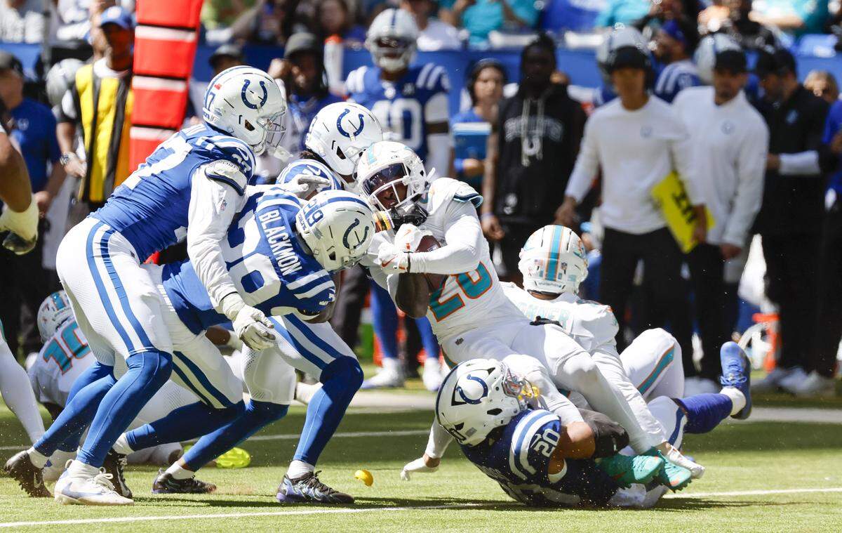 Miami Dolphins running back De'Von Achane (28) is brought down by Indianapolis Colts safety Nick Cross (20), cornerback Kenny Moore II (23), and cornerback Mekhi Blackmon (29) during the first half of an NFL game at Lucas Oil Stadium on Sunday, September 7, 2025, in Indianapolis, Indiana.