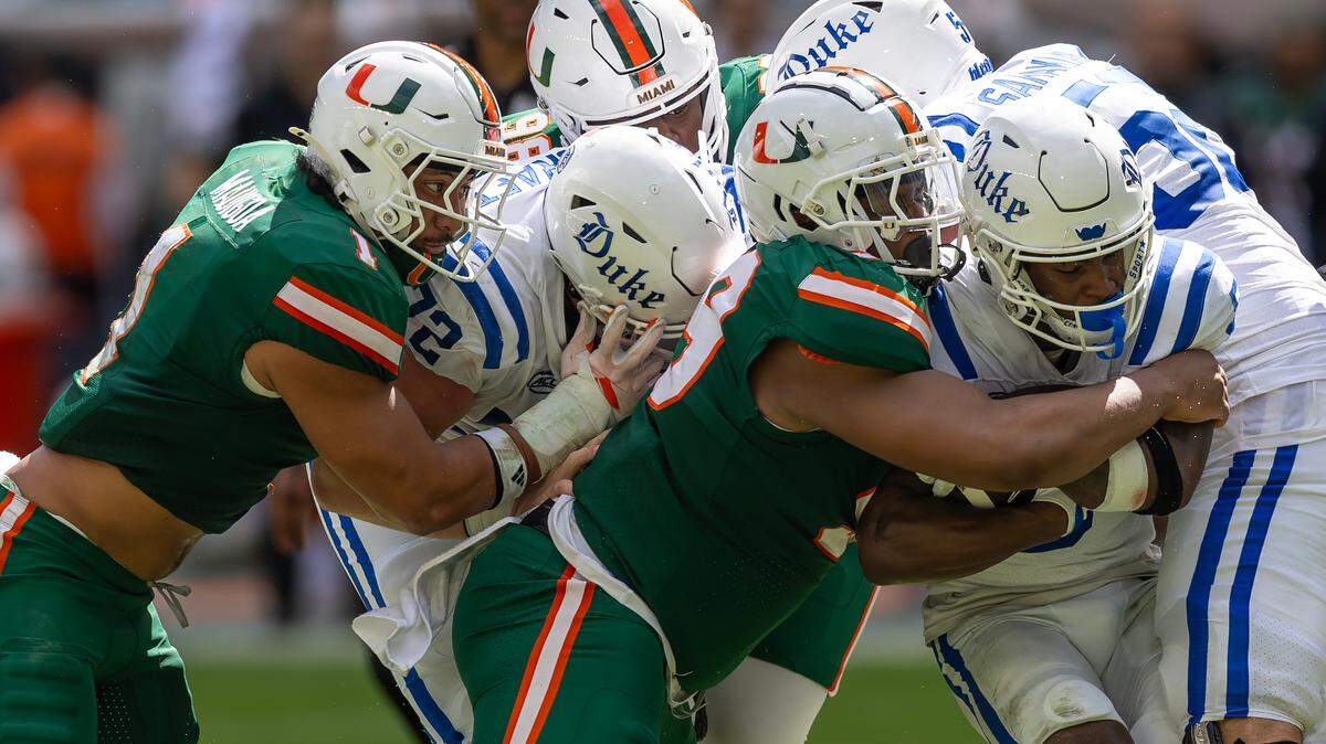 Miami Hurricanes linebacker Francisco Mauigoa (1) and Hurricanes defensive linemen Ahmad Moten Sr. (99) and Justin Scott (98) attempt to stop Duke Blue Devils running back Peyton Jones (5) during the first half of an ACC football game at Hard Rock Stadium on Saturday, Nov. 2, 2024, in Miami Gardens, Fla.
