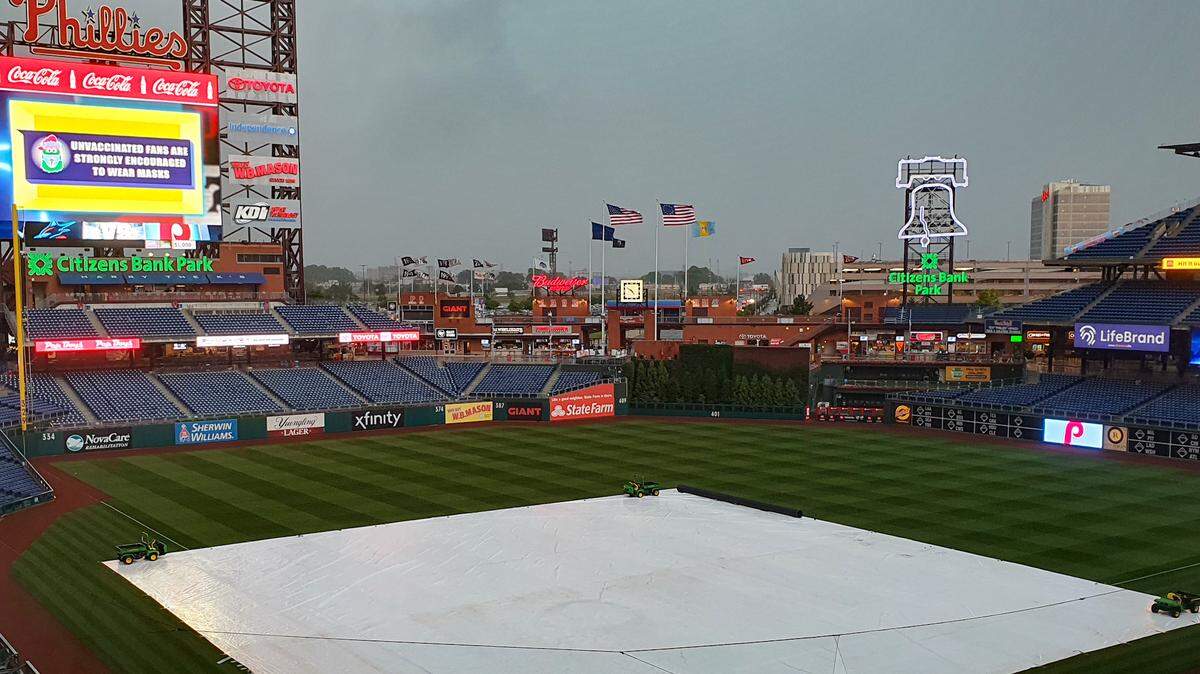 A tarp covers the infield at Citizens Bank Park on Thursday, July 1, 2021, as rain falls in Philadelphia.