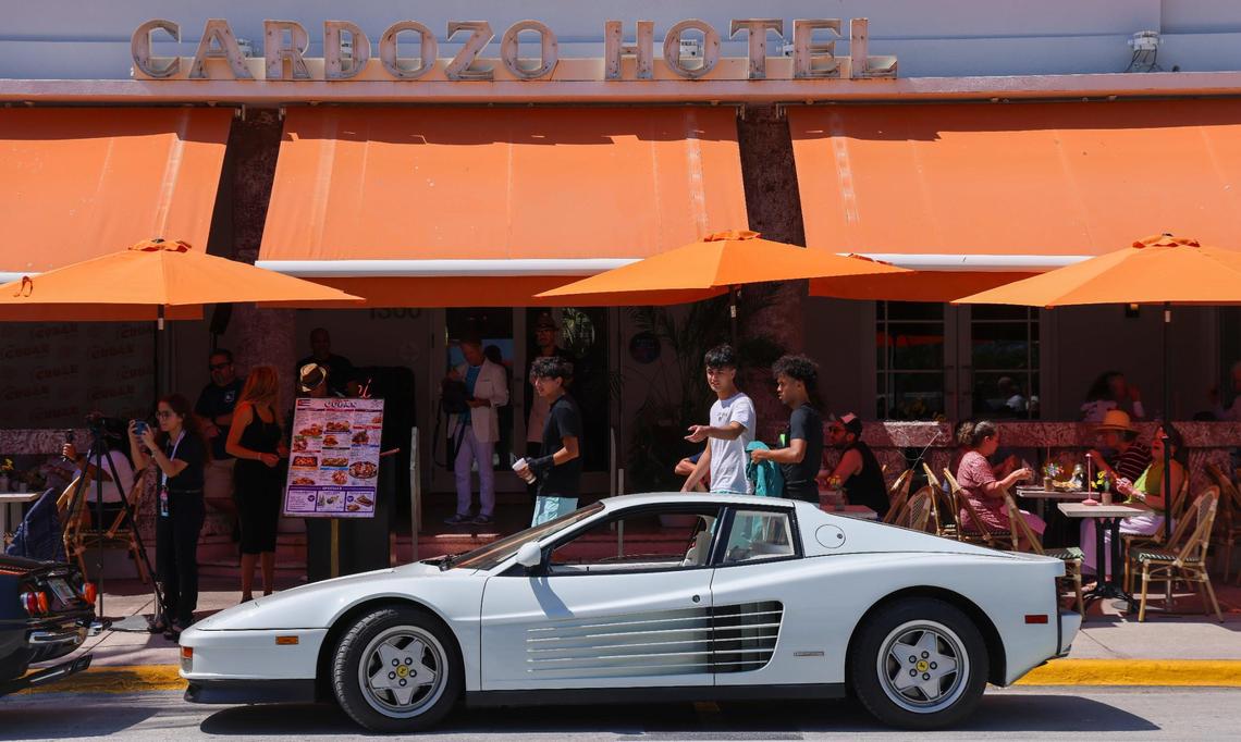 A group of young men pass by the Ferrari Testarossa made famous by the TV show “Miami Vice” as a video promoting a reunion is shot on Ocean Drive during spring break in Miami Beach on Thursday, March 13, 2025.