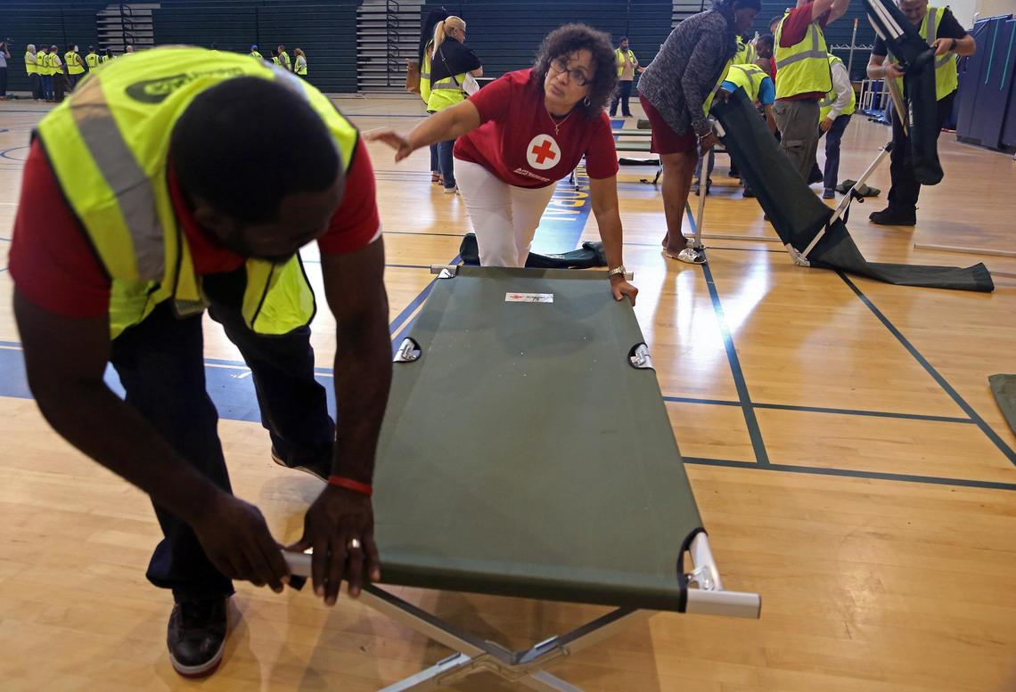 Miami-Dade emergency management coordinator Lou Alexis, left, get instructions from Red Cross volunteer Sonia Ramos, center, on how to assemble a cot during the Miami-Dade and the American Red Cross training exercises for hurricane preparation inside Ronald Reagan High School's gym in Doral, Florida, on Thursday, June 28, 2018.