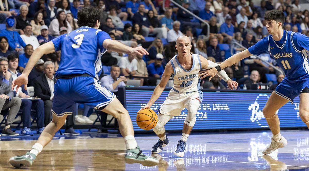 Nova Southeastern Sharks guard Dallas Graziani (12) drives the ball as Rollins Tars guard Michael Kalina (3) and guard Ricky Ghedini (11) defend in the first half of their Sunshine State Conference Championship quarterfinal basketball game at the Rick Case Arena on Tuesday, March 3, 2026, in Davie, Fla.