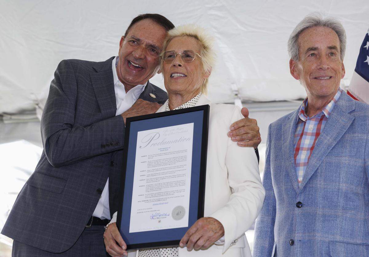 Mayor Dean Trantalis, left, hugs Diana Nyad, center, after he and Commissioner Steven Glassman, right, hand her a proclamation during a ceremony naming a street marker on Las Olas after Nyad, the only person to swim from Cuba to Florida without a shark cage, on Thursday, Nov. 6, 2025, at Las Olas Oceanside Park in Fort Lauderdale, Fla. 