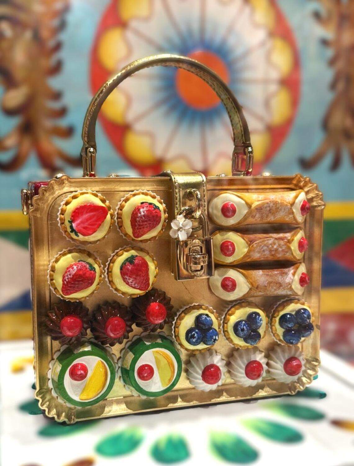 En la exposición dedicada a Sicilia, un extravagante bolso está decorado con cannoli enjoyados y otros dulces regionales.
