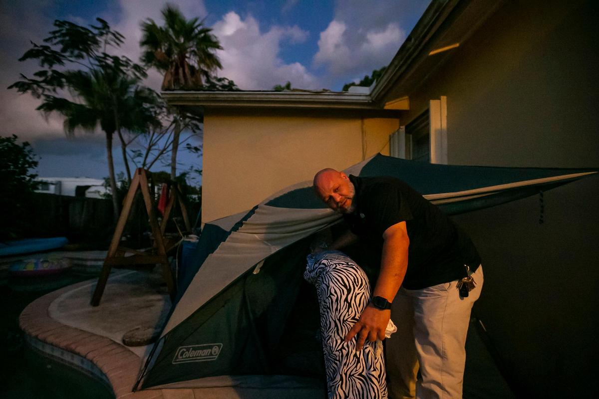John Delgado puts a mattress in his tent before heading to bed outside his home in Homestead.