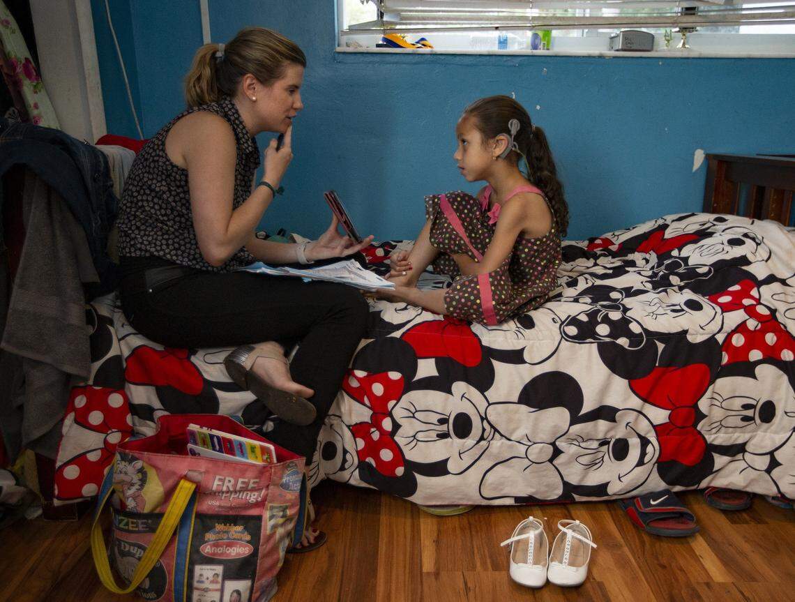 Speech-language pathologist Christina Lally works with Marcia Guillou, 6, at the child’s home. Marcia was born deaf. She and her five siblings, also born deaf, have been fitted with bilateral cochlear implants allowing them to hear. The surgeries were done at the University of Miami Health System.