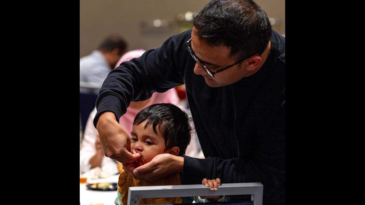 Maureen, 1, is fed by her father Agnan, 35, during an interfaith iftar dinner at Florida International University. Fasting is one of the five main pillars of Islam, and Muslims observing Ramadan will refrain from eating and drinking from sunrise to sunset, then break the fast with an iftar dinner.