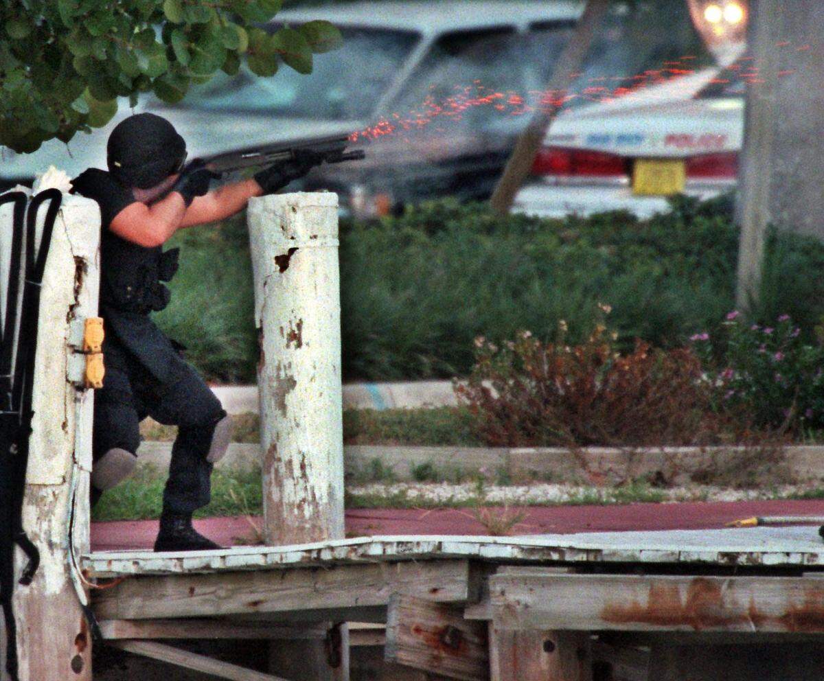 In this file photo from July 23, 1997, a SWAT team officer fires tear gas into the houseboat where murder suspect Andrew Cunanan was later found dead of a self-inflicted gunshot wound. Cunanan killed Gianni Versace eight days earlier.