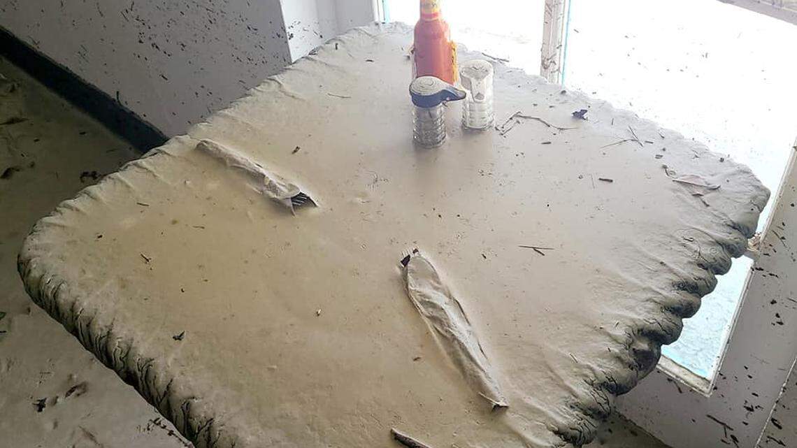 Table settings, including salt and pepper shakers, a bottle of hot sauce, and silverware wrapped in paper napkins, seem to sit near normal, unless you look closer, despite a nearly 6-foot storm surge that swept through The Lighthouse Café in Sanibel, Florida, on Sept. 28, 2022. Owner Dan Billheimer posted this photo to the restaurant’s Facebook page on Oct. 6.