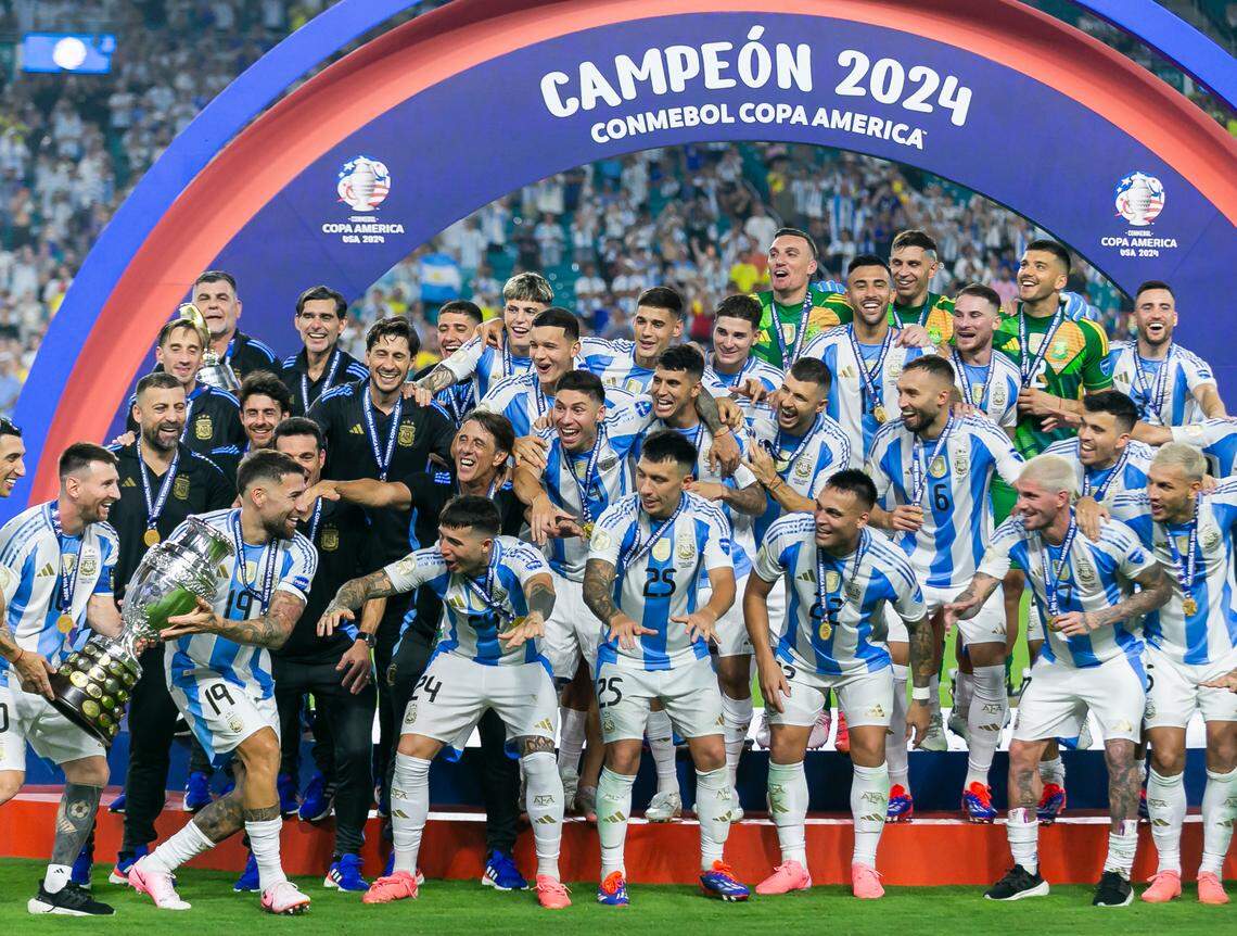 Argentina forward Lionel Messi (10) and defender Nicolás Otamendi (19) hold the trophy as they prepare to celebrate with their teammates after defeating Colombia in their Copa America 2024 Final soccer match at Hard Rock Stadium on Sunday, July 14, 2024, in Miami Gardens, Fla.