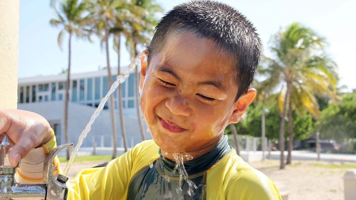 Ethan Allisade takes a shower to stay cool until getting to the hotel as he visited Miami Beach from Washington with his family as the National Weather Service issued a heat advisory for the first time in seven years for South Florida in July.