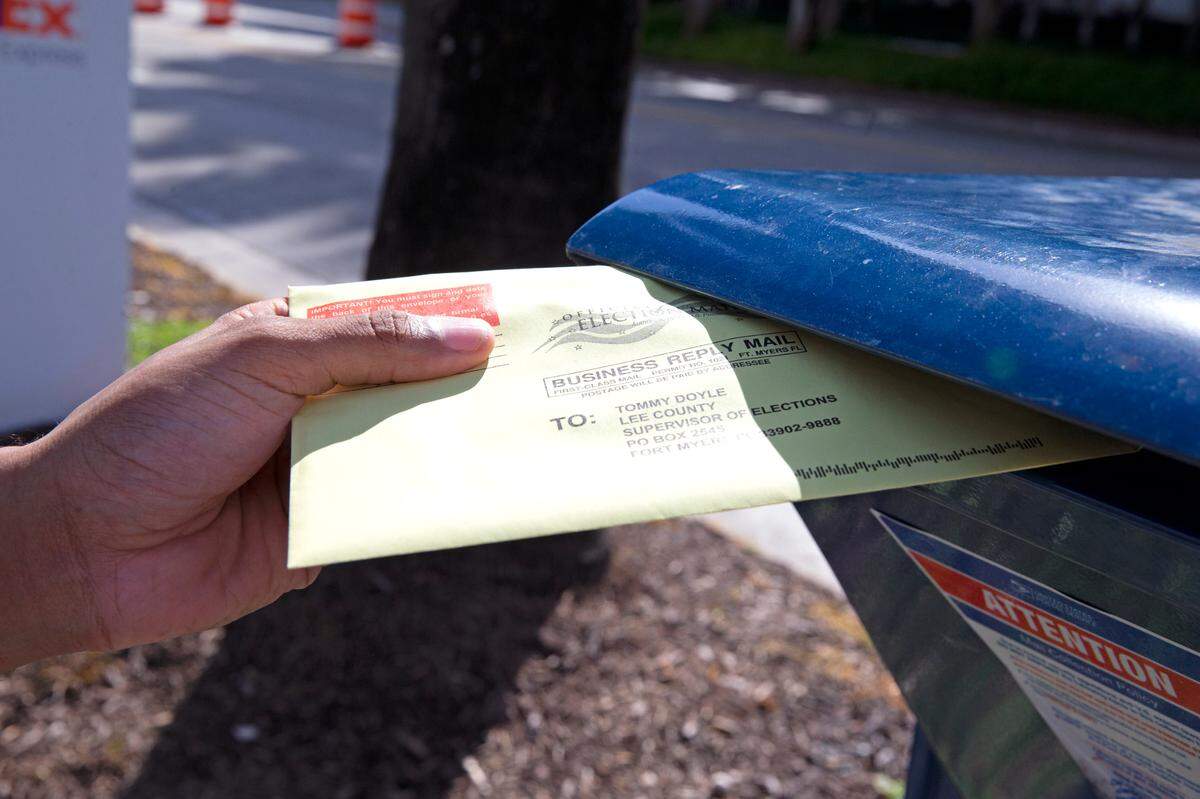 File photo of a voter depositing a ballot in a mail collection box outside Miami Beach City Hall during early voting for the general election on Oct. 28, 2020, in Miami Beach.