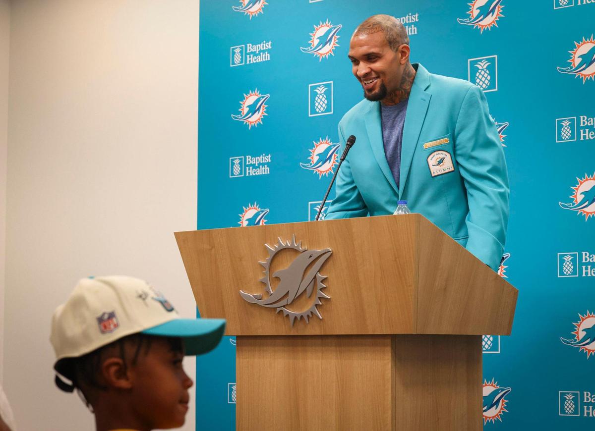 Mike Pouncey speaks while his son, Kayden, front, listens during a press conference announcing his retirement from the Miami Dolphins on Thursday, March 9, 2023, in Miami Gardens.