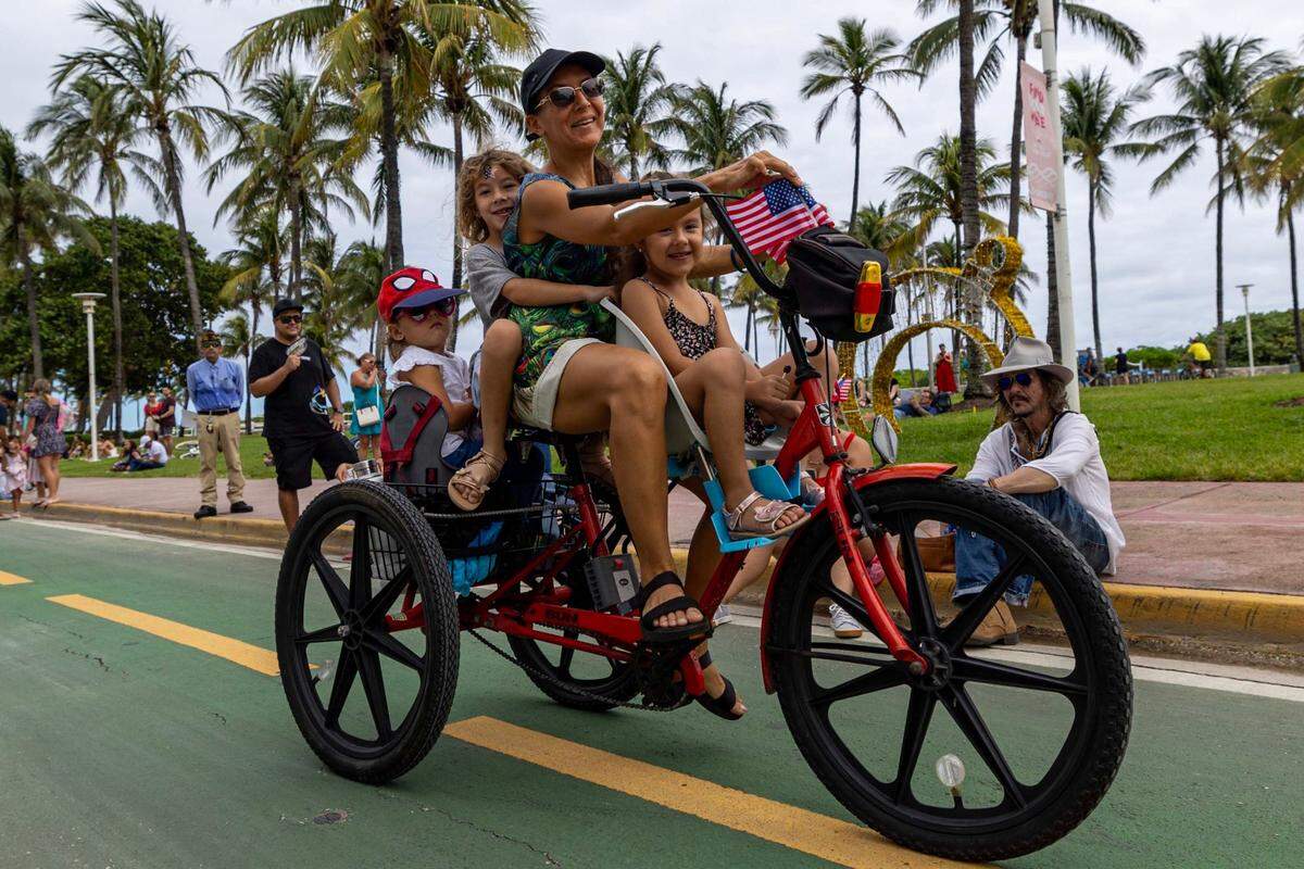 Miami Beach resident Liuba Iglesias pedals her children around during the 16th Annual Veterans Day Parade off Ocean Drive on Monday, Nov. 11, 2024, in Miami Beach, Fla.