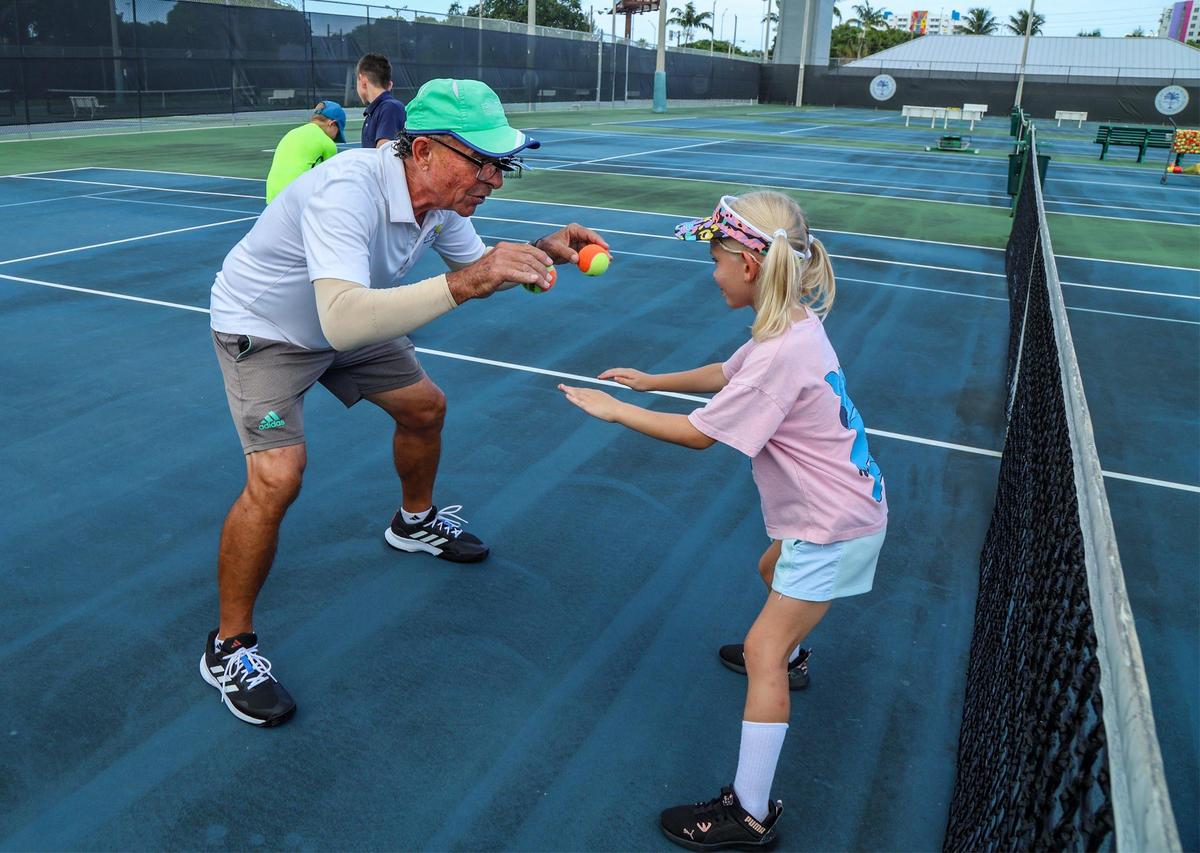 Coach Mario Osorio trains with student Alisa Drofa who recently arrived from Ukraine, during a session of the First Serve Miami Program at Moore Park in Miami, on Friday, October 06, 2023.