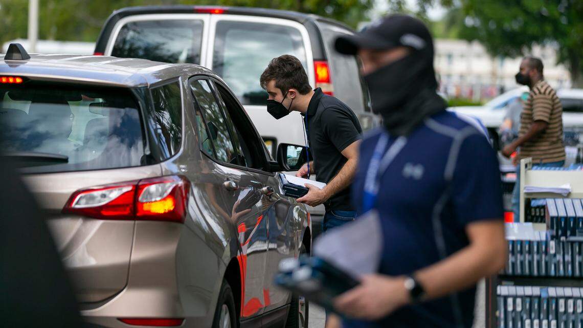 Ryan Loeffler, left, a Broward County employee, hands out free at-home rapid COVID-19 tests at South Regional/Broward College Library in Pembroke Pines, Florida on Saturday, Jan. 8, 2022.
