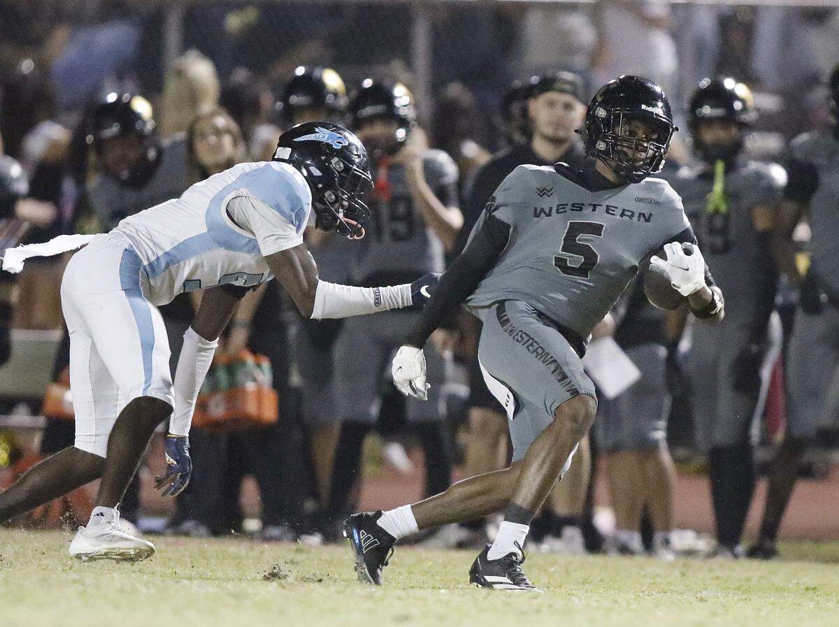 Western Wildcats wide receiver Russell George (5) attempts to break free from West Broward Bobcats defender during the football game on Thursday, October 30, 2025 at Western HS in Davie. Andrew Uloza / for Miami Herald