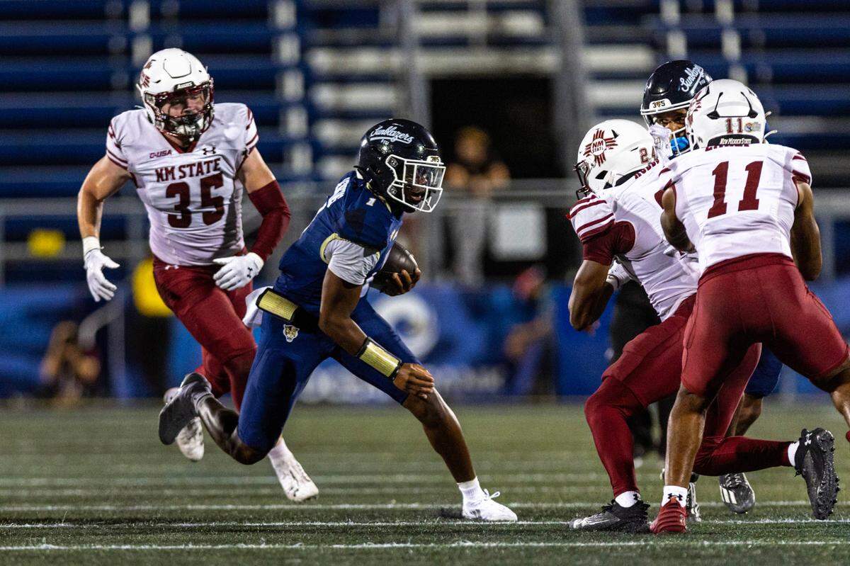 Florida International University Panthers quarterback Keyone Jenkins (1) scrambles as New Mexico State Aggies defenders swarm around him during the second half of an NCAA Conference USA football game at Pitbull Stadium on Tuesday, October 29, 2024, in Miami, Fla. 