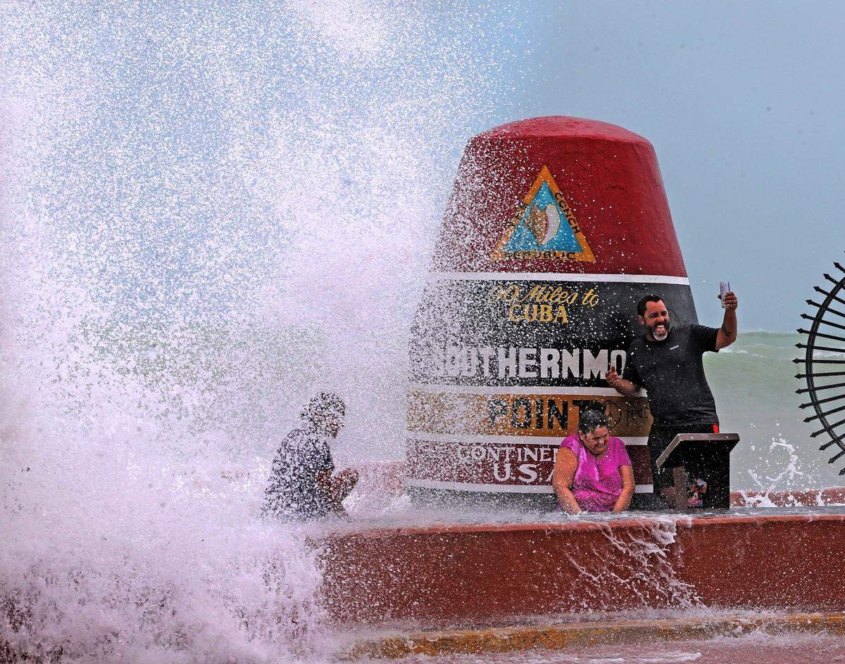 Key West resident Pedro Lara takes a selfie in front of the Southernmost Point marker as waves from Hurricane Irma crash over the wall, September 9, 2017.