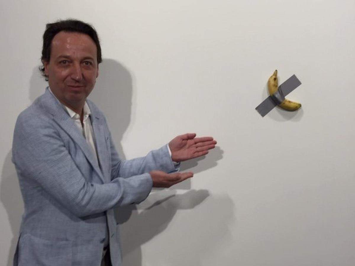 Gallerist Emmanuel Perrotin shows off ‘Comedian,’ a work by Italian bad-boy artist Maurizio Cattelan that consists of a banana taped to the wall. The piece, one of three bananas on exhibit at the Art Basel Miami Beach fair, sold for $120,000, Perrotin said.