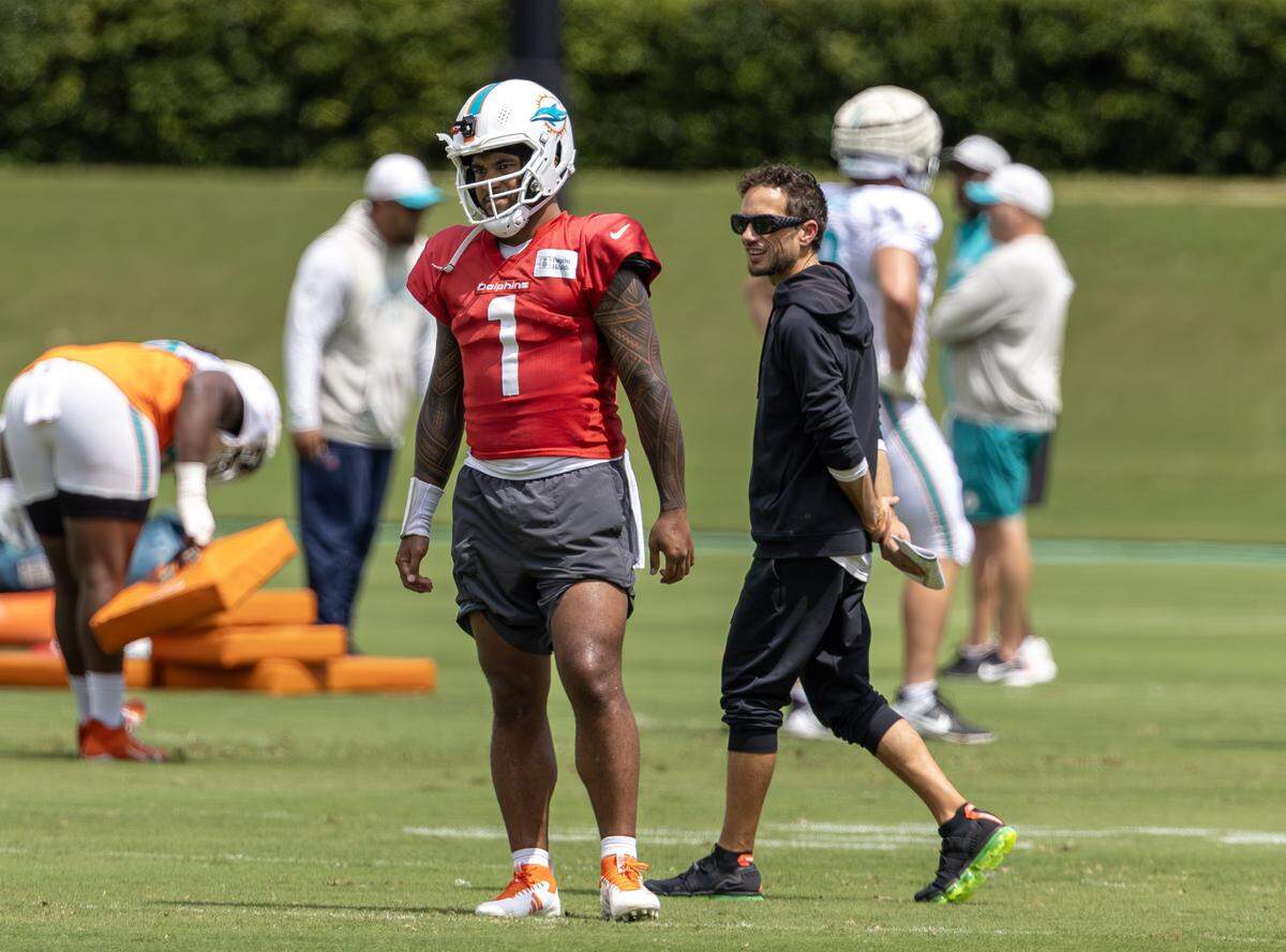 Miami Dolphins head coach Mike McDaniel walks past quarterback Tua Tagovailoa (1) during practice at the Baptist Health Training Complex on Thursday, Sept. 25, 2025, in Miami Gardens, Fla.