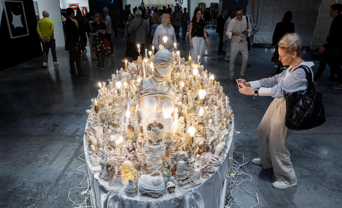 Elena Kazlas, from Boston, takes a photo of ‘Bound Angel’ by Portia Munson during Art Basel at the Miami Beach Convention Center on Wednesday, Dec. 4, 2024, in Miami Beach, Fla.