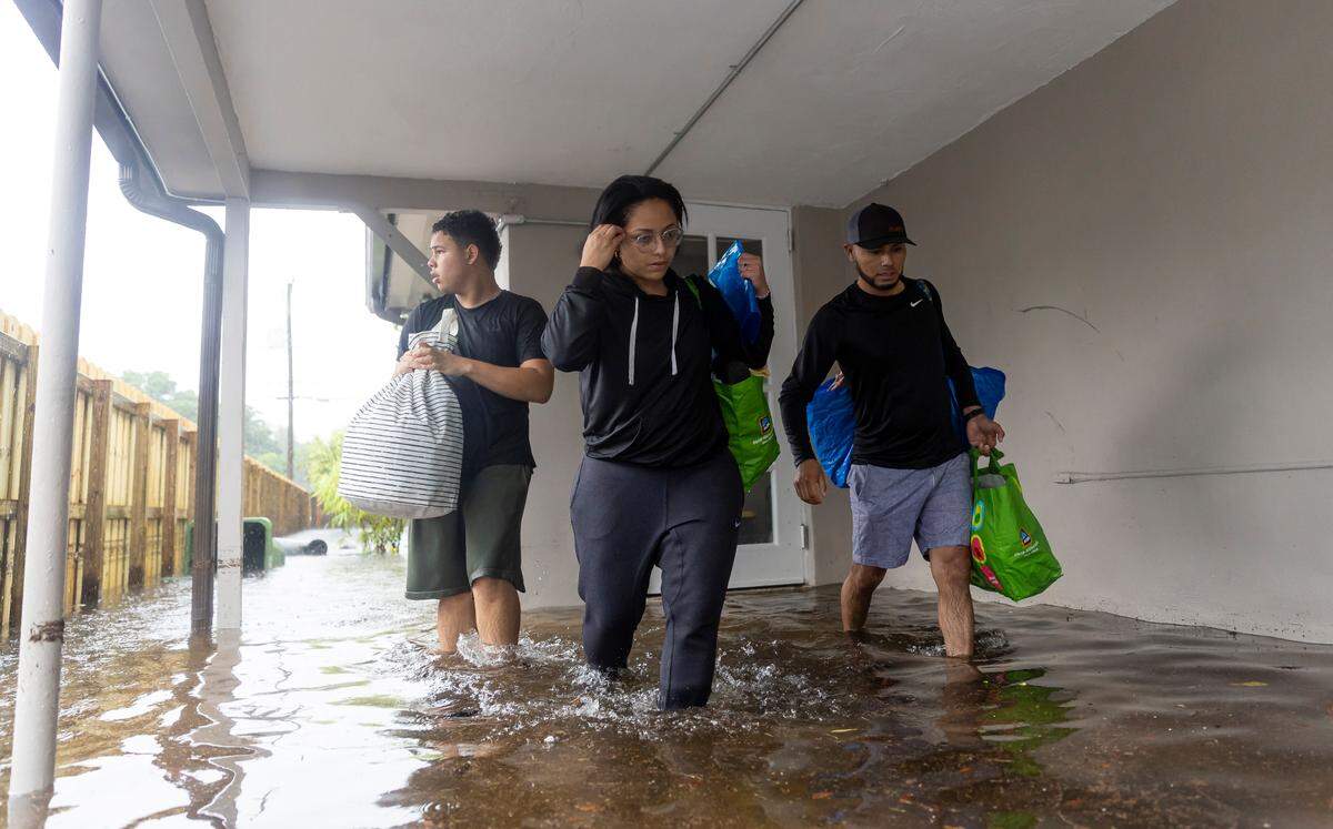 From left, Santiago Rojas, 15, Denis Mendez, 32, and Isain Lopez, 33, leave their flooded home in the Fort Lauderdale’s Edgewood neighborhood after a torrential downpour severely flooded streets, partially submerging houses and cars across South Florida.