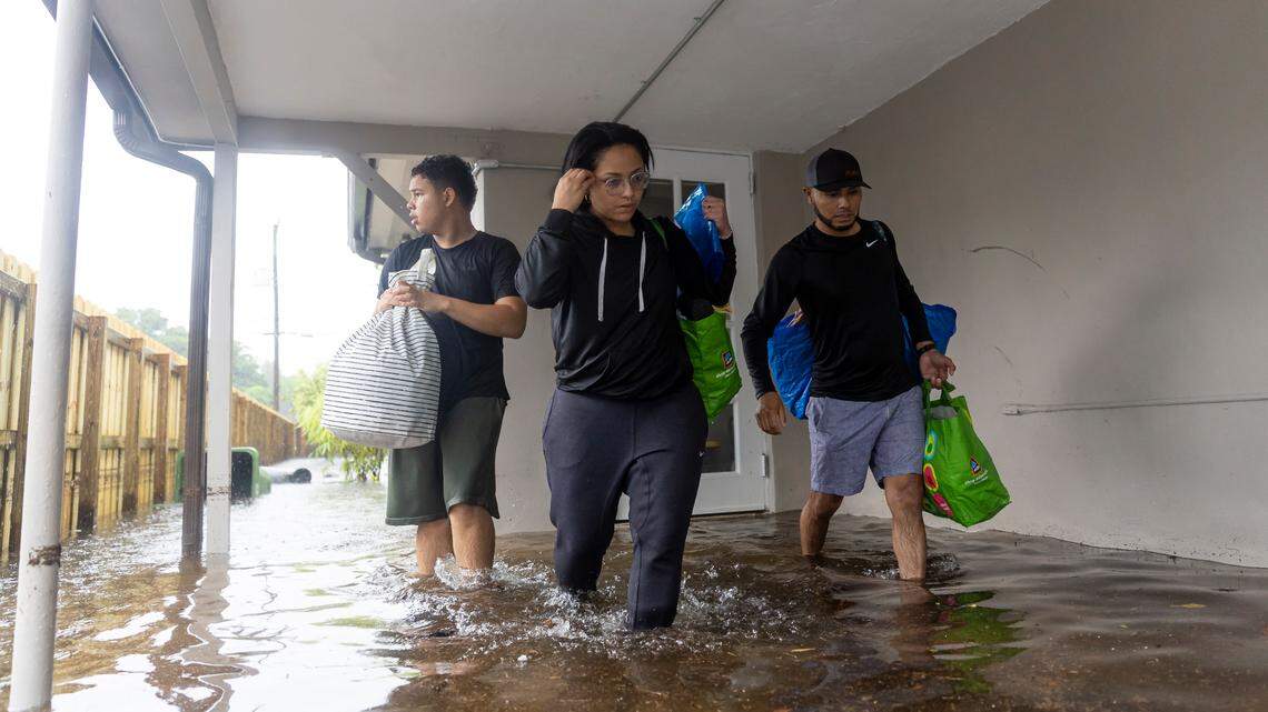 From left: Santiago Rojas, 15, Denis Mendez, 32, and Isain Lopez, 33, leave their flooded home in the Edgewood neighborhood in Fort Lauderdale, Fla. on Thursday, April 13, 2023. A torrential downpour severely flooded streets, houses and cars across South Florida.
