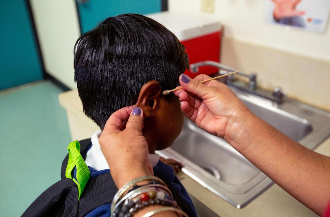 A school instructor helps a student from a secret migrant camp in South Miami-Dade. The kids are helped to clean up and get clean clothes and shoes when needed.