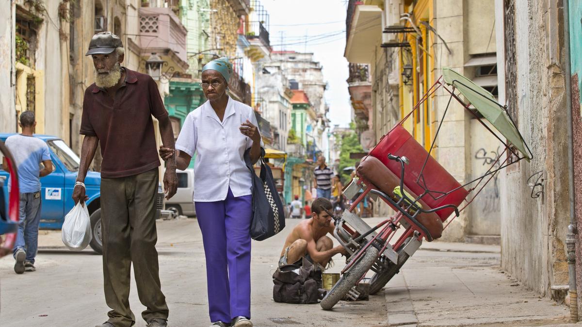 Foto de archivo de ancianos cubanos caminando en La Habana mientras otro cubano repara un bicitaxi, el jueves 24 de septiembre de 2015.