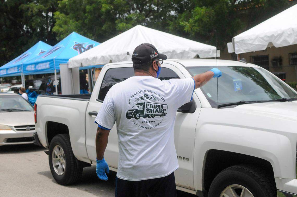 A Farm Share volunteer directs traffic during a Miami Marlins food distribution at Marlins Park on Wednesday, June 2, 2020.