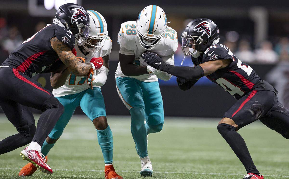Miami Dolphins running back De'Von Achane (28) runs with the ball as Atlanta Falcons cornerback A.J. Terrell Jr. (24) goes for the tackle in the second half of their NFL game at Mercedes-Benz Stadium on Sunday, Oct. 26, 2025, in Atlanta, Ga.