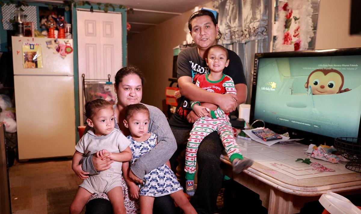 Elizabeth Rosario and Joey Puente with their 2-year-old twins (from left) Lilah and Lilith and daughter Luna, age 4, at their home in Homestead. Their Wish Book needs include beds for the twins who are in therapy for developmental delays. They also need a small dining room table, a tuneup for their 16-year-old car and repairs to the bathroom and roof of their trailer.