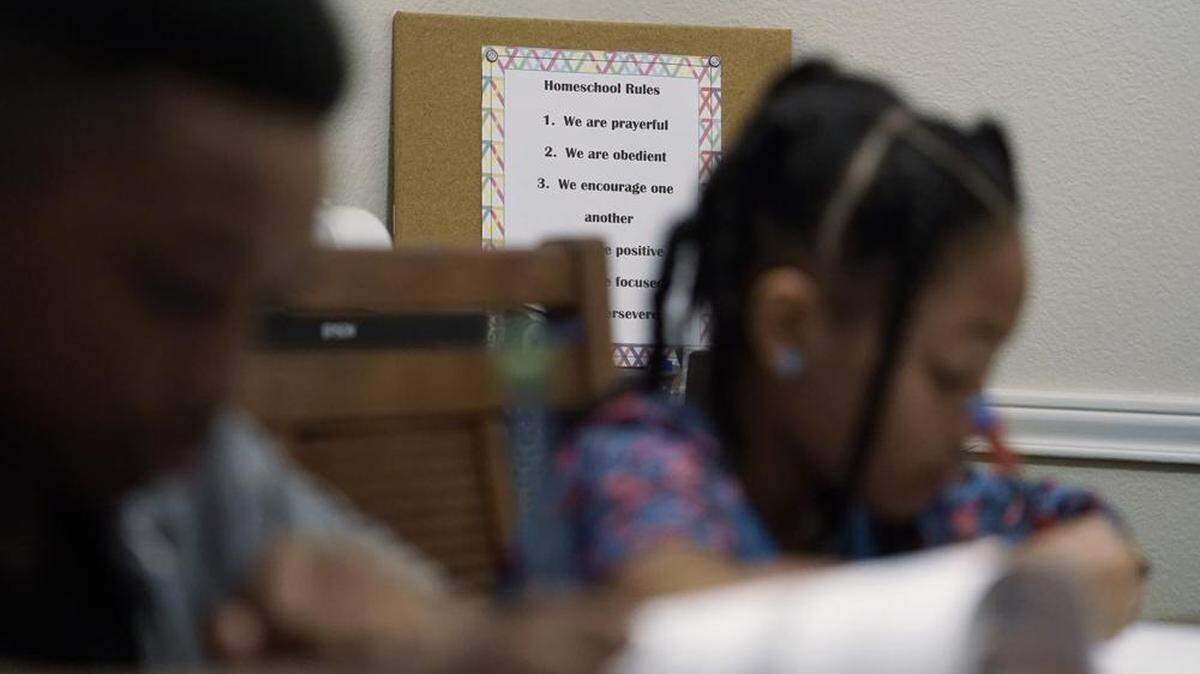 Jacoby Brown, 11, and sister Felicity, 9, they study math lessons at their Austin, Texas, home, with the family rules for homeschool posted behind.
