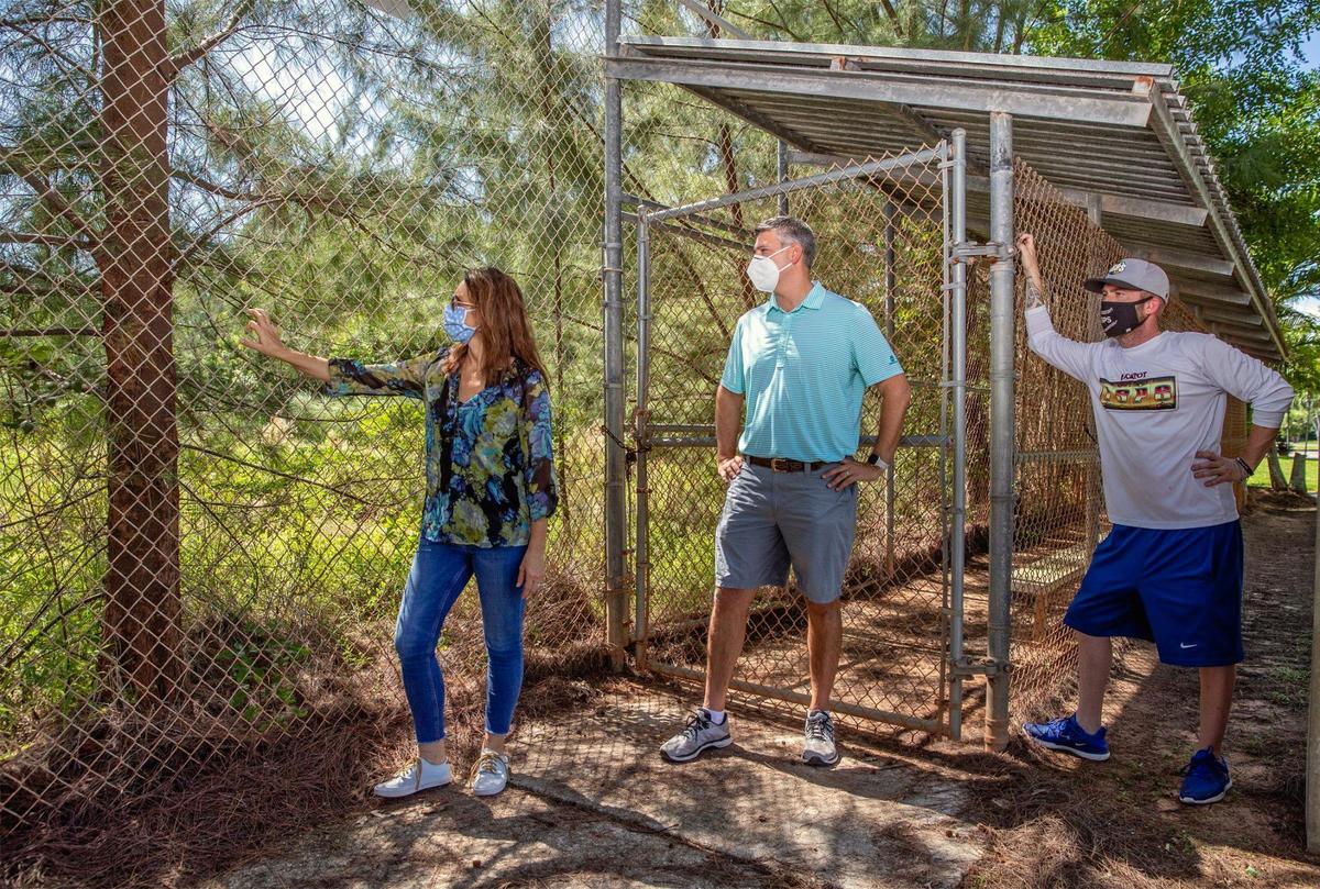 From left, Julie Jeffries, Chapman Field Park neighbor, Ethan Shapiro, founder of Save Chapman Field Park, and Manuel T. Ferrero, commissioner of the International Slow Pitch Softball league, look at Field 2, one of three overgrown diamonds that have been closed for six years.