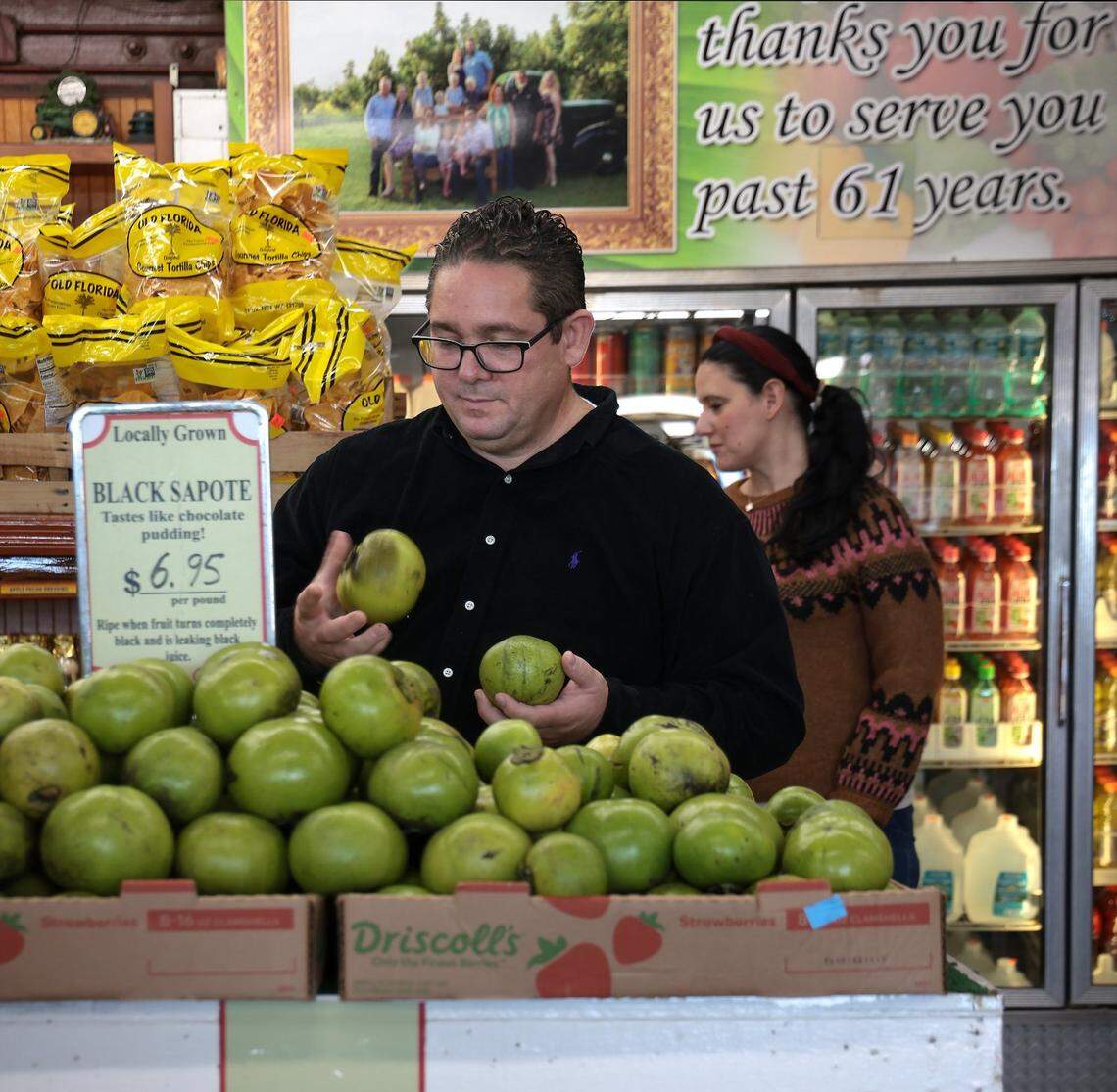 Miami resident Ariel Coro, 45, shops for locally grown black sapote at Robert Is Here fruit stand in Homestead, Florida. Though prices are up slightly, Coro is buying several pounds due to the sapotes scarcity on Thursday, December 2, 2021.