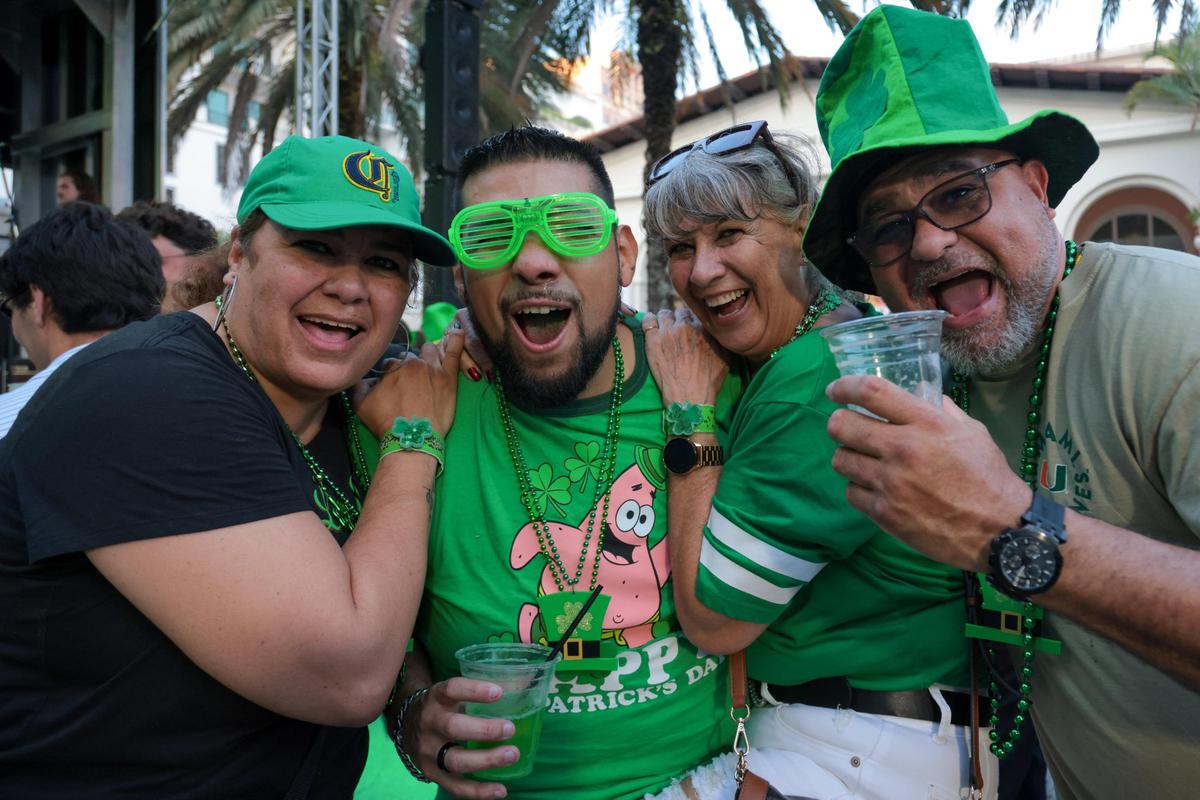 Maribel Rodriguez, left, Dave Wayne, center, Dora Martinez, and Armando Macet, right, react while dancing at John Martin’s 32nd Annual St. Patrick’s Day Street Festival in Coral Gables, Florida, Saturday, March 15, 2025.