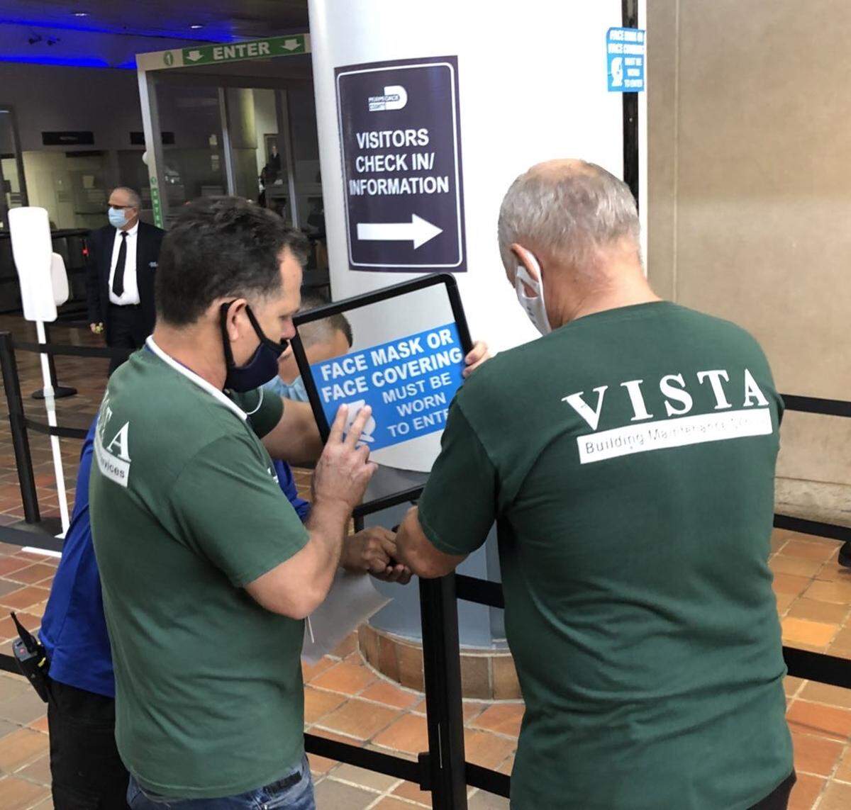 Facilities workers reinstall mask signs at Miami-Dade County’s Stephen P. Clark Center in downtown Miami on Wednesday, July 28, 2021, minutes after Mayor Daniella Levine Cava ordered a return to masking rules at county facilities for the first time since May.